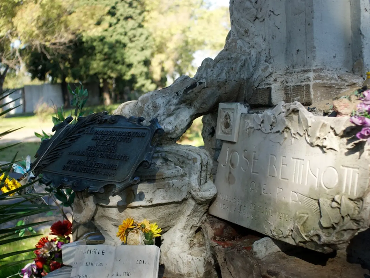 In this image, we can see name stones contains some text. There are some flowers and leafs in the...