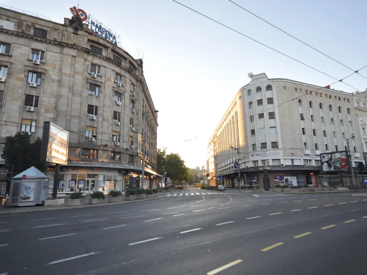 Here we can see buildings with windows. In-front of these buildings there are hoarding, trees and...