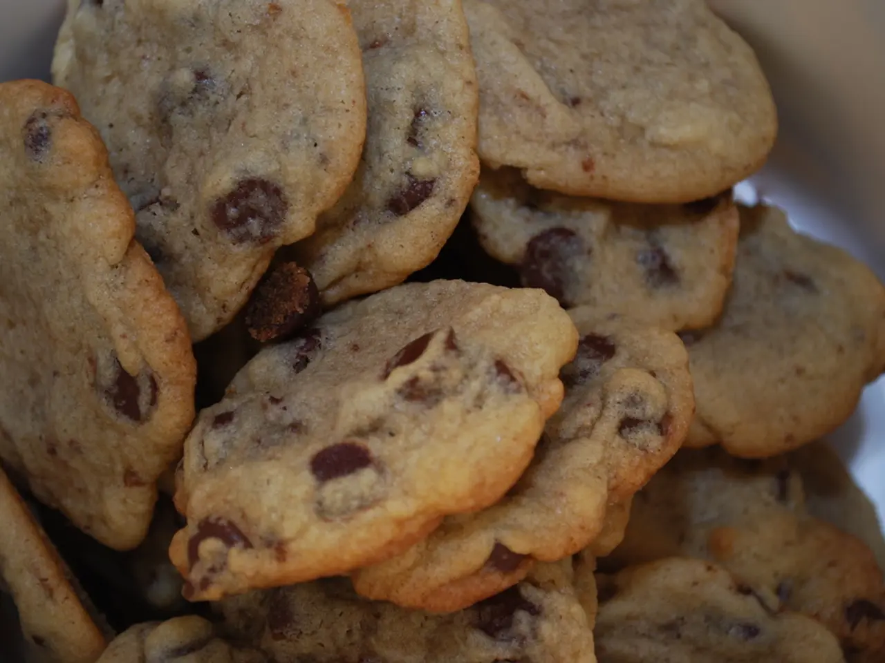 In this image there are so many cookies in the box. On the cookies there are choc chips.