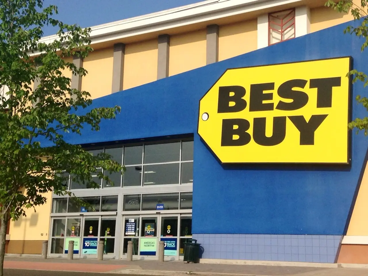 In this image I can see a building where best buy is written on it. I can also see number of trees...