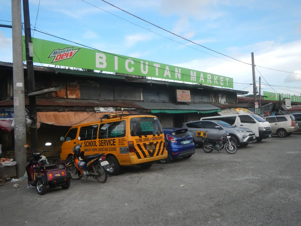The image shows a bustling bicutan market in Cebu City, Philippines, with vehicles on the road,...