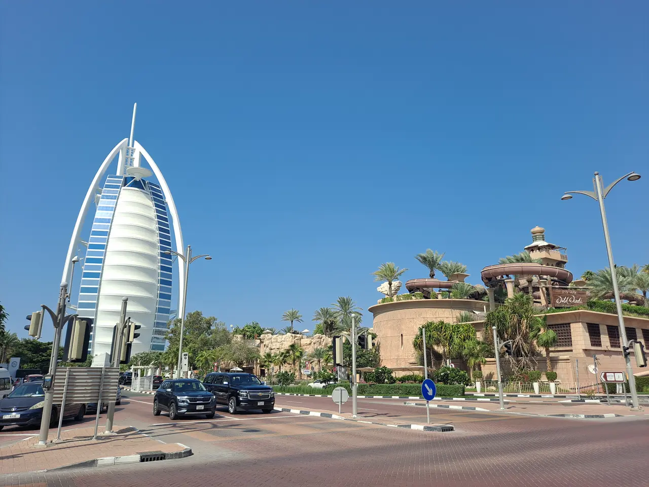 The image shows the iconic Burj Al Arab Hotel in Dubai, UAE. We can see vehicles on the road, light...