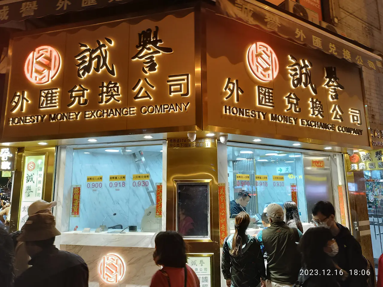 The image shows a group of people standing outside of a building at night, illuminated by lights...