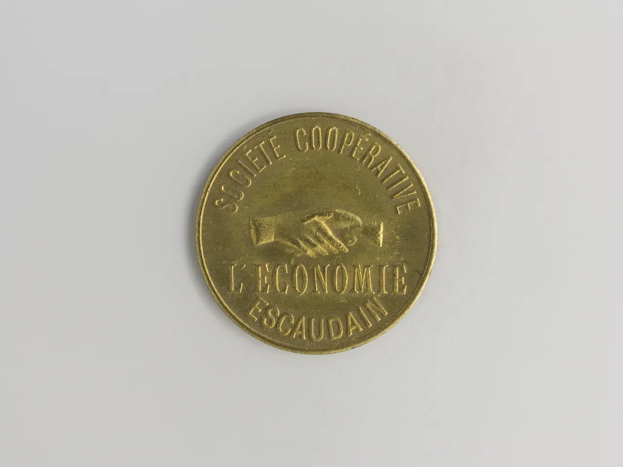 The image shows a gold coin with the words "Societe Cooperative L'Economie Escaudain" written on it...