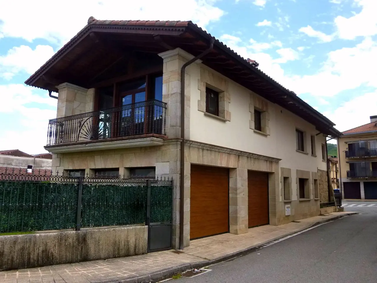 The image shows a large house with a lot of windows and a fence on the side of it, situated on a...