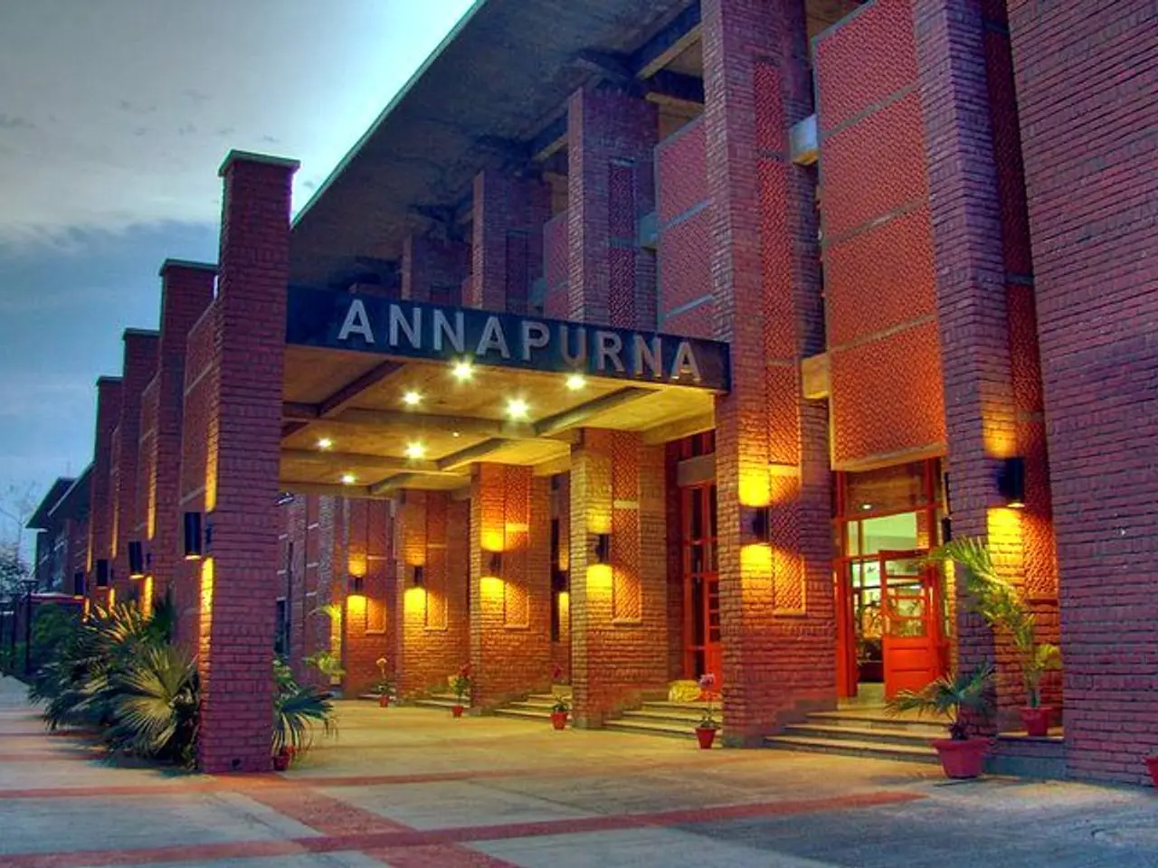 The image shows the Annapurna Hotel in Hyderabad, India. It is a building with pillars, lights,...