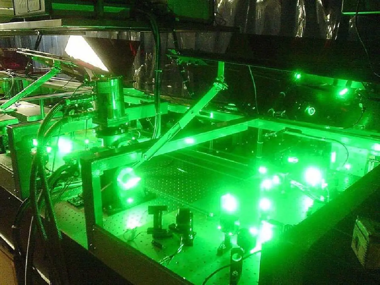 The image shows a machine sitting on top of a table with a green light emanating from it. The...