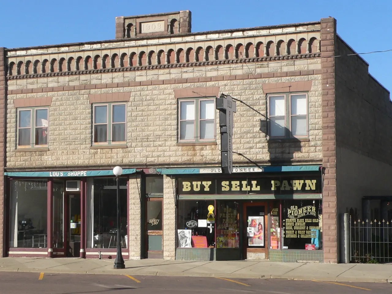 The image shows a building with a sign that reads "Buy Sell Pawn" on the corner of a street,...