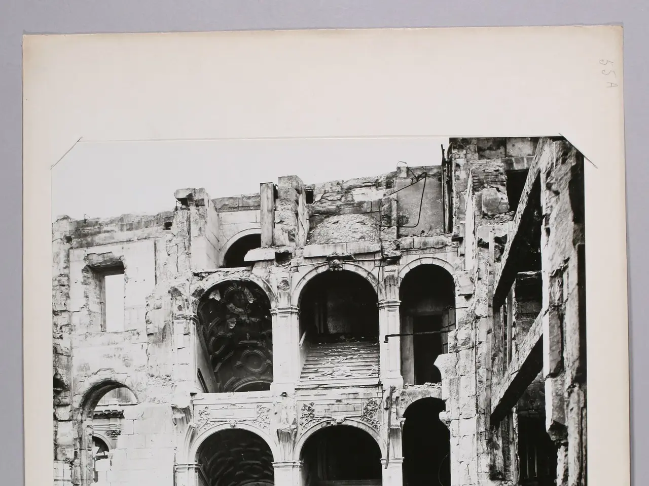 The image shows a black and white photo of an old building on a white surface. The building appears...