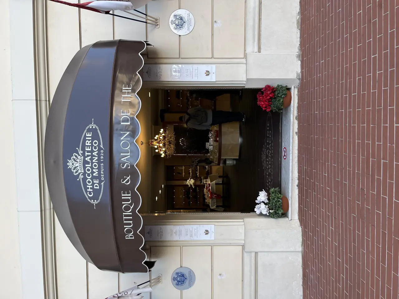 The image shows a building with a sign that reads "Boutique & Salon de Monaco" on the side of it....