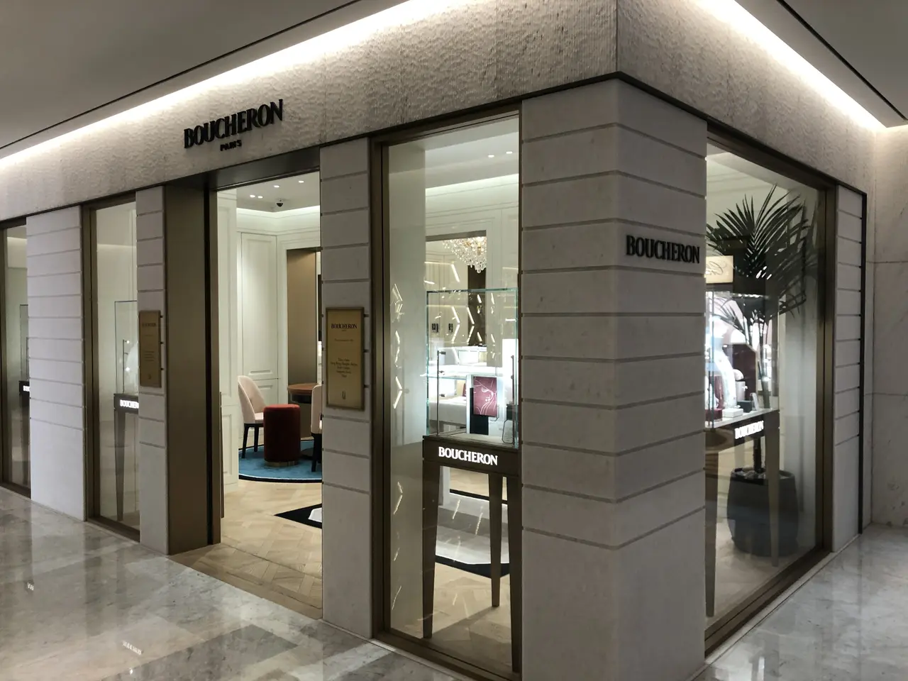 The image shows the entrance to a boutique in a shopping mall, with glass walls and doors, text on...