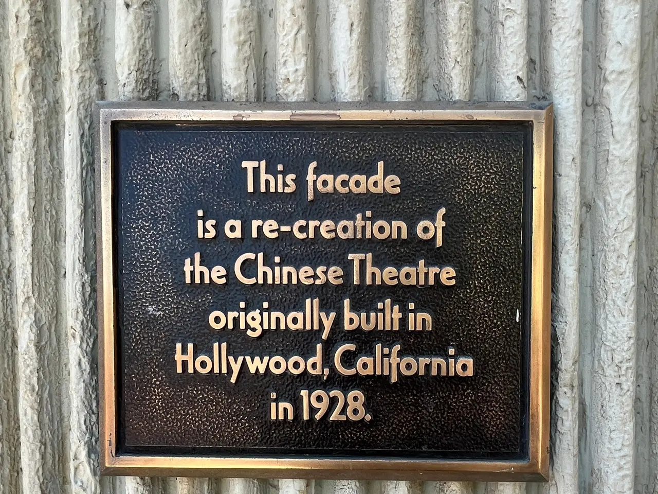 The image shows a plaque on the side of a building that reads "This facade is a re-creation of the...