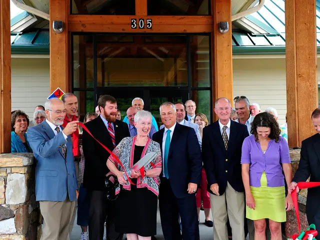 In this picture there is a group of men and women standing and smiling. In the front there is a...