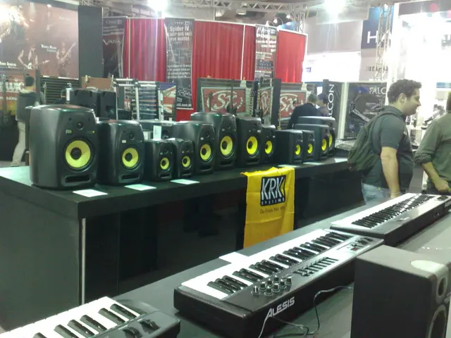 In the image we can see there are people standing and at the back there are speakers kept on the...