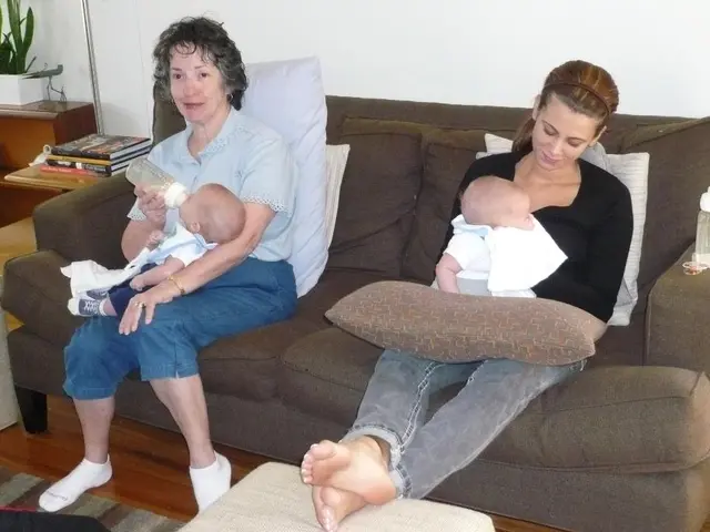 In the center of the picture there is a couch, on the couch there are two women sitting holding...