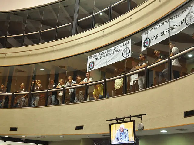 In this image we can see a building. Bottom of the image TV screen is present and from the building...