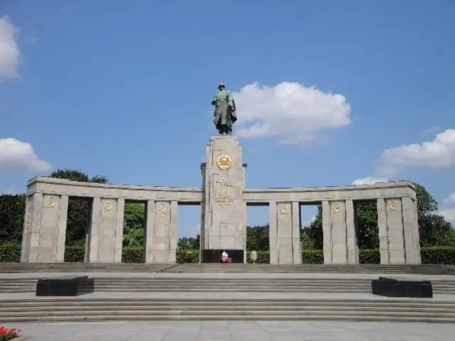 In this image we can see a memorial. There are pillars and there is a statue on the top of the...