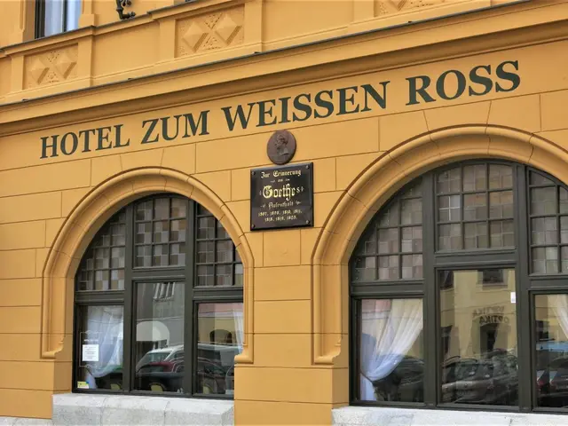The image shows the Hotel Zum Weissen Ross in Vienna, Austria. It is a building with glass windows...