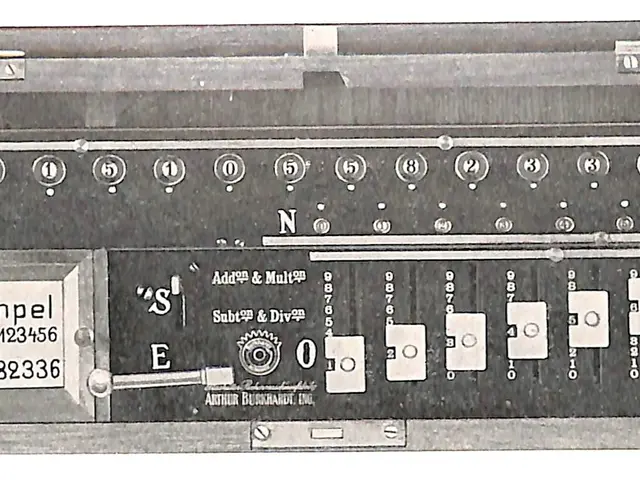 The image shows a black and white photo of an electronic device with a key on it, which appears to...