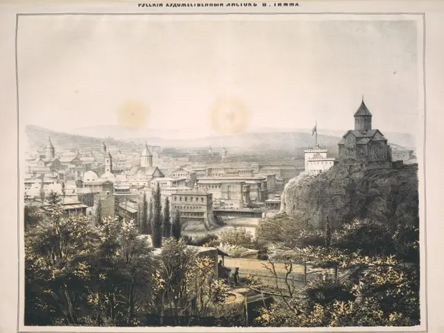 The image shows a view of the city of Tbilisi from the top of a hill, with trees, buildings, hills,...