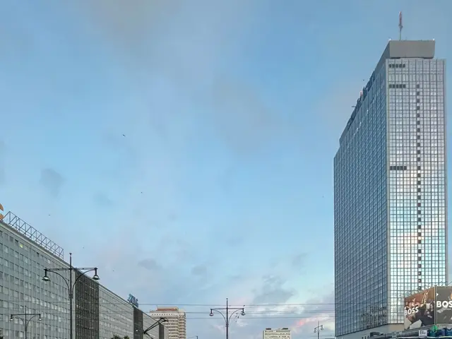 The image shows a yellow and black tram on a city street with tall buildings in the background....