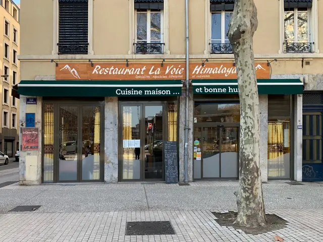 The image shows a building with glass doors and windows, a signboard with text on it, a street...