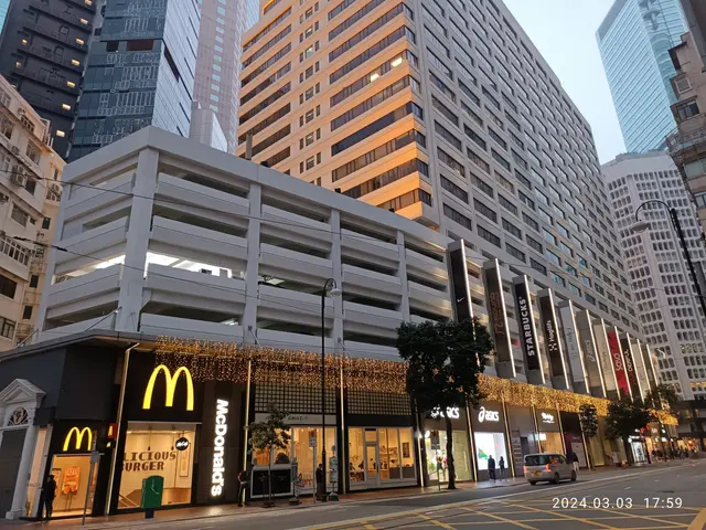 The image shows a McDonald's restaurant in the middle of a bustling city street, surrounded by tall...