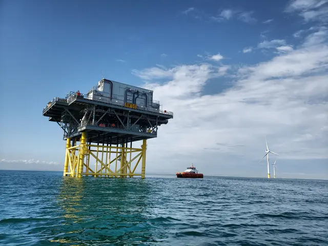 The image shows an offshore wind farm in the middle of the ocean, with a boat in the foreground and...