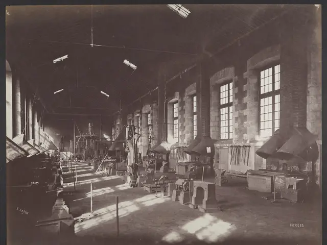 The image shows an old black and white photo of a factory with windows on the right and left side...