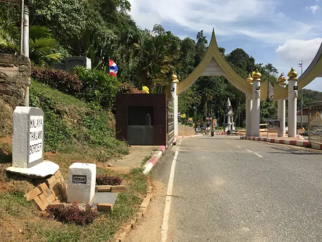 The image shows the entrance to the Thai Embassy in Thailand, with a road leading up to it. On...