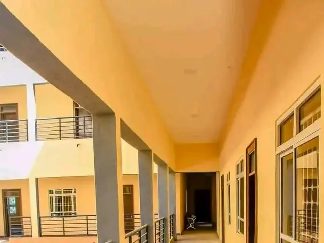 The image shows a building with windows, doors, pillars, railings, and a long hallway with a tiled...