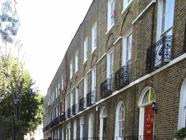 The image shows a row of terraced houses on a street in London, with windows, doors, railings,...