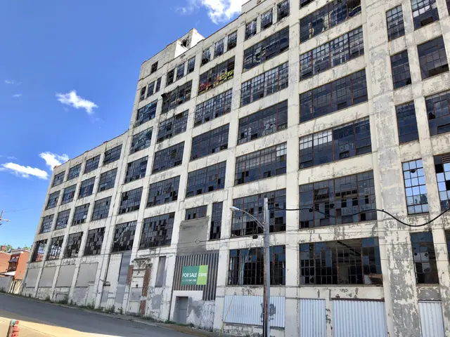 The image shows an old building with many windows on the side of it, surrounded by street poles,...