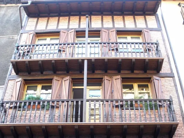The image shows an old building with many windows and balconies in Strasbourg, France. The building...