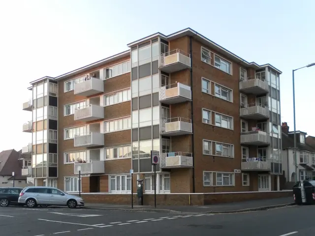 The image shows a large apartment building with many windows and balconies on the side of it,...