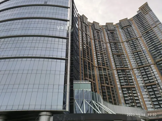 The image shows a tall building with many windows in the middle of it, surrounded by a sky with...