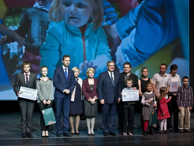 The image shows a group of people standing on top of a stage, with some of them holding bags and...