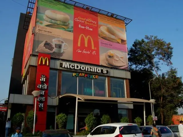 The image shows a McDonald's restaurant in Mumbai, India, with a large billboard on the side of the...